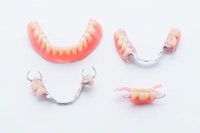 The image displays four pairs of dentures with visible teeth and gums arranged on a white surface.